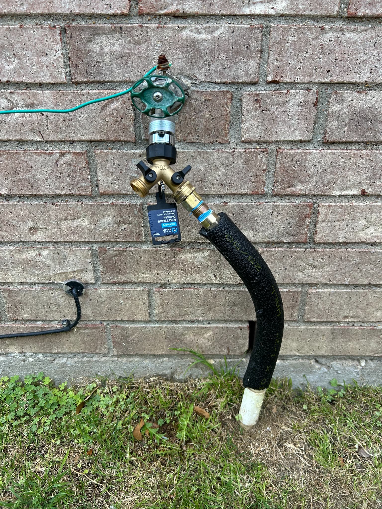 Exterior plumbing water connection at a brick home